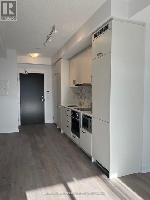 A modern kitchen with white cabinets and a black door.