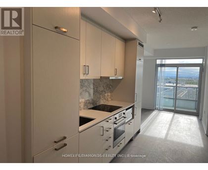 A kitchen with white cabinets and a marble backsplash.