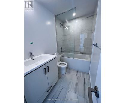 A white bathroom with a glass shower stall and a toilet.