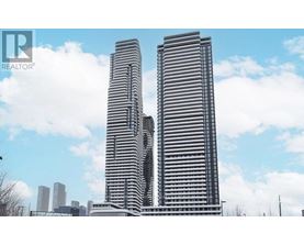 Two tall buildings with a blue sky and clouds in the background.