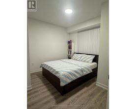 A bedroom with a bed, pillows, and a nightstand with a lamp.
