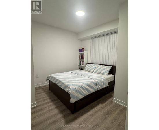 A bedroom with a bed, pillows, and a nightstand with a lamp.