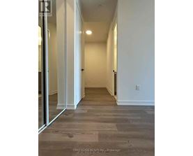 A long hallway with wood floors and white walls.