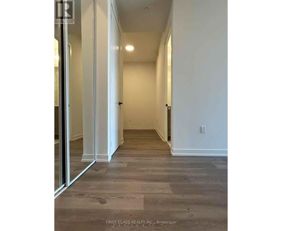 A long hallway with wood floors and white walls.