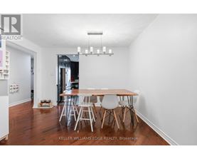 A dining room with a wooden table and white chairs.
