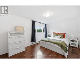 A bedroom with a bed, nightstand, and a window with curtains.