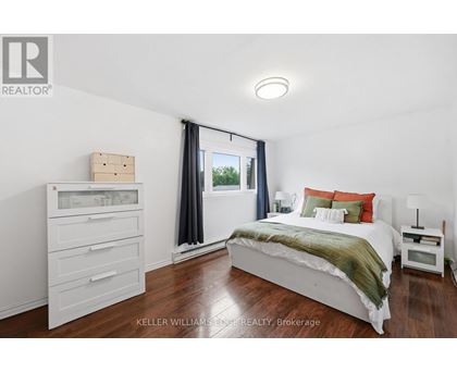 A bedroom with a bed, nightstand, and a window with curtains.