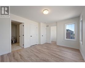 A spacious room with wood flooring and white walls.