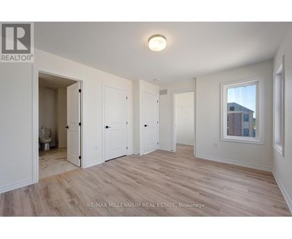 A spacious room with wood flooring and white walls.