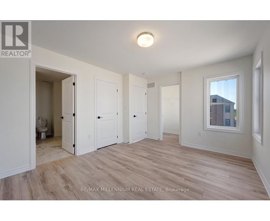 A spacious room with wood flooring and white walls.