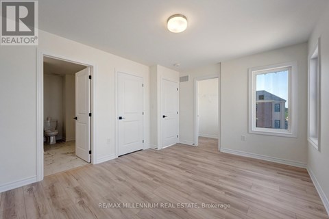 A spacious room with wood flooring and white walls.