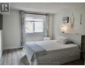 A bedroom with a large bed and a window with curtains.