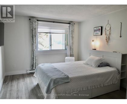 A bedroom with a large bed and a window with curtains.