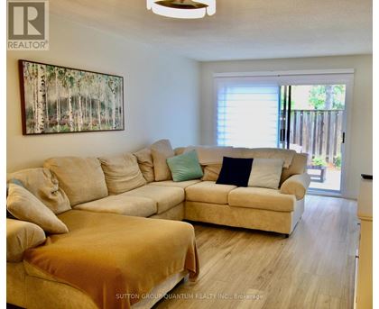 A living room with a large beige couch and a painting on the wall.