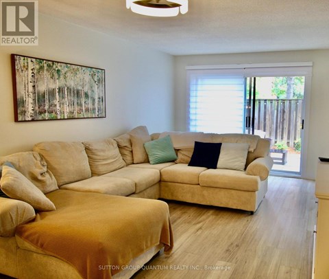 A living room with a large beige couch and a painting on the wall.