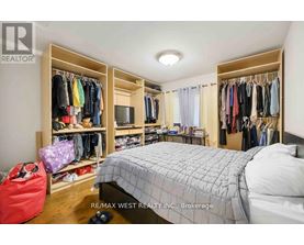 A bedroom with a large bed, a closet with clothes, and a red bag on the floor.