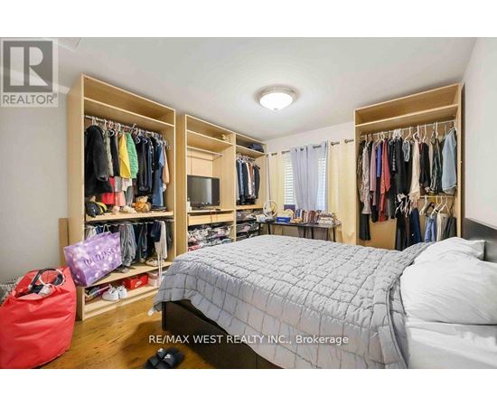 A bedroom with a large bed, a closet with clothes, and a red bag on the floor.