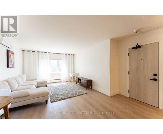 A living room with a white couch and a rug in the middle.