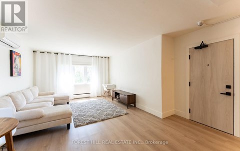 A living room with a white couch and a rug in the middle.