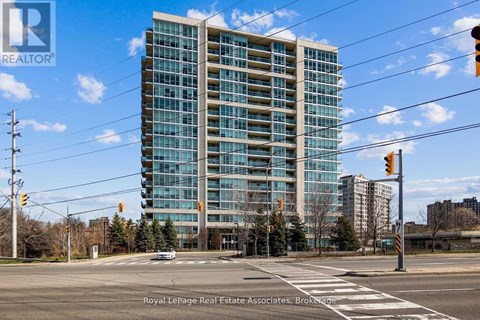 A tall building with many windows is in the background of a street scene.