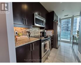 A kitchen with black cabinets and a brick backsplash.