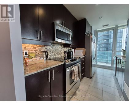 A kitchen with black cabinets and a brick backsplash.