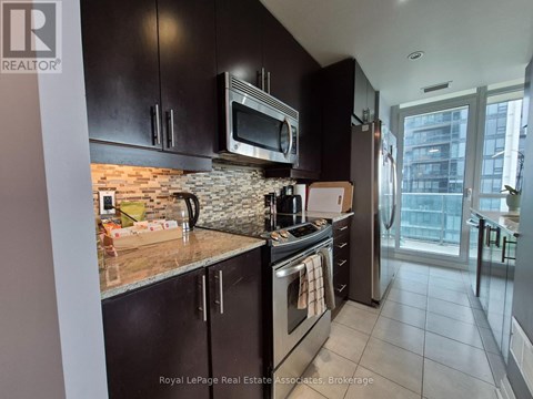 A kitchen with black cabinets and a brick backsplash.