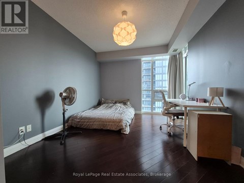 A bedroom with a bed, desk, and chair.