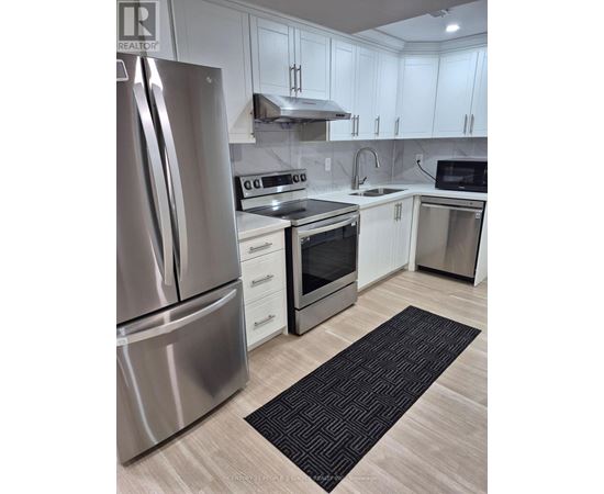 A modern kitchen with a stainless steel refrigerator and white cabinets.