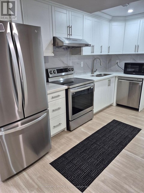 A modern kitchen with a stainless steel refrigerator and white cabinets.