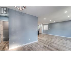 A spacious room with wooden flooring and a large mirror on the wall.