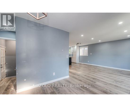 A spacious room with wooden flooring and a large mirror on the wall.