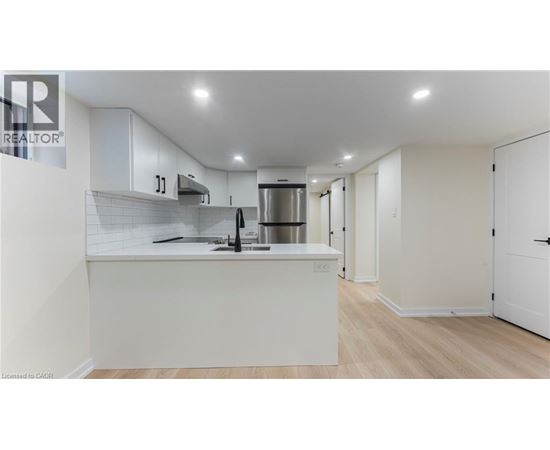 A modern kitchen with white cabinets and a stainless steel refrigerator.