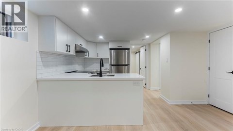 A modern kitchen with white cabinets and a stainless steel refrigerator.