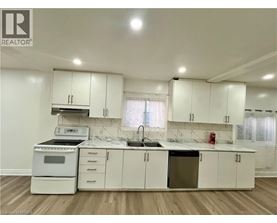 A white kitchen with a sink, stove, and cabinets.