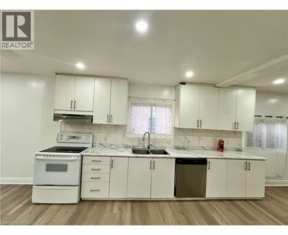 A white kitchen with a sink, stove, and cabinets.