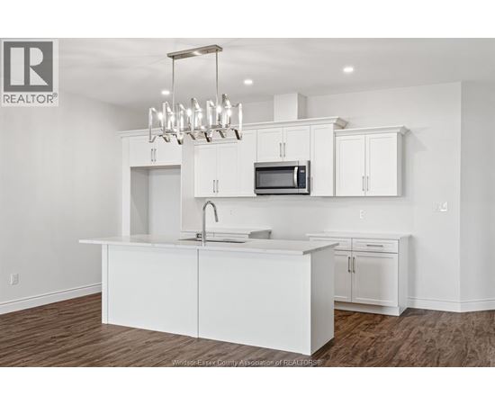 A white kitchen with a microwave and a sink.