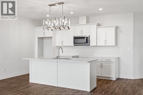 A white kitchen with a microwave and a sink.