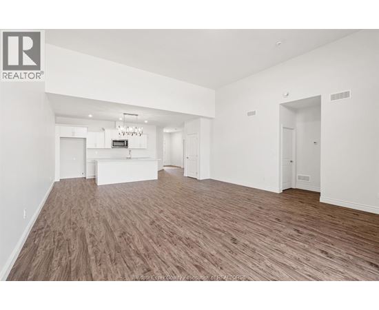 A spacious room with wooden flooring and white walls.