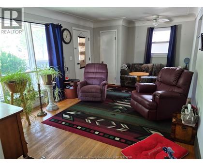 A living room with a rug and two chairs.