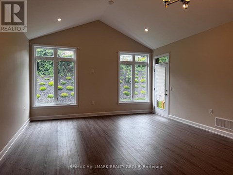 A room with a large window and a door is empty and waiting to be furnished.