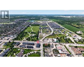 An aerial view of a residential area with a large green space in the middle and houses scattered throughout.