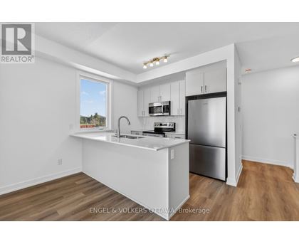 A kitchen with white cabinets and a stainless steel refrigerator.