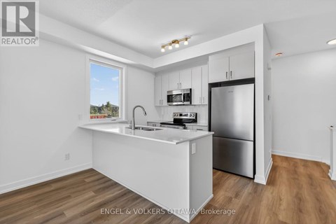A kitchen with white cabinets and a stainless steel refrigerator.