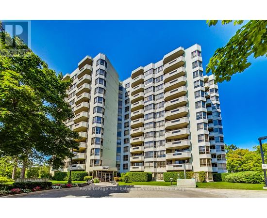 A large, modern apartment building with a well-maintained garden in front.