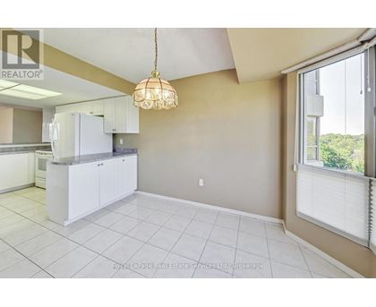 A well-lit kitchen with white cabinets and a tiled floor.