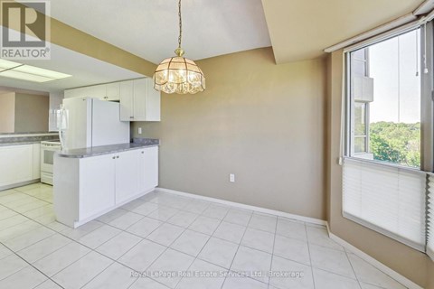 A well-lit kitchen with white cabinets and a tiled floor.