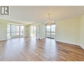 A large, empty room with wooden floors and a chandelier.