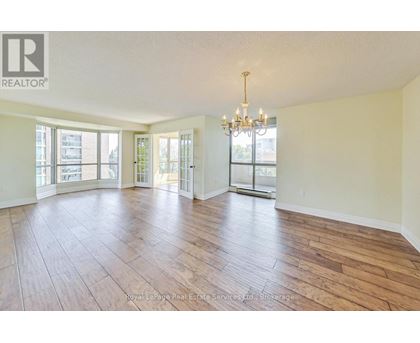 A large, empty room with wooden floors and a chandelier.