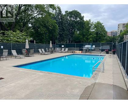 A large outdoor swimming pool surrounded by a fence and lounge chairs.